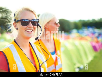 Sicherstellen, dass alles reibungslos läuft. Zwei junge Sicherheitsassistentinnen stehen auf einem Campingplatz bei einem Musikfestival im Freien. Stockfoto