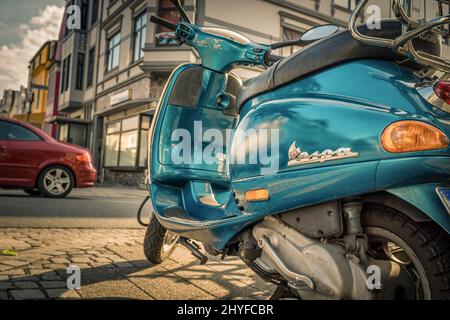 Türkisfarbener Vespa-Roller auf dem Bürgersteig in Bremen, Deutschland, geparkt Stockfoto