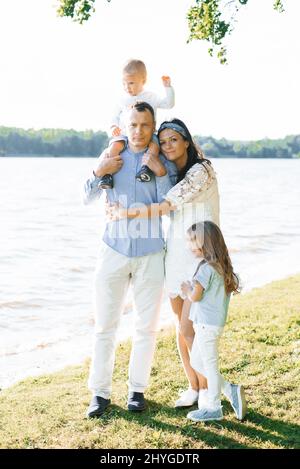 Eine glückliche Familie mit zwei Kindern hat Spaß im Sommer am See Stockfoto