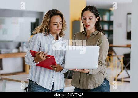 Zwei lateinische Geschäftsfrau im mittleren Alter, die sich im Büro in Mexiko, Lateinamerika, unterhalten und beraten Stockfoto