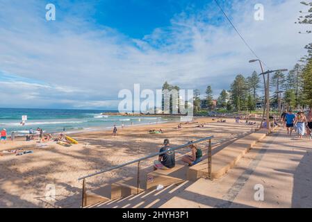 Am späten Nachmittag im Sommer schwimmen und spazieren Sie am Dee Why Beach in Sydney, New South Wales, Australien, entlang der Promenade Stockfoto