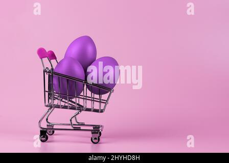 Ostereier im Warenkorb auf Fliederhintergrund, Lavendelfarbe. Stockfoto