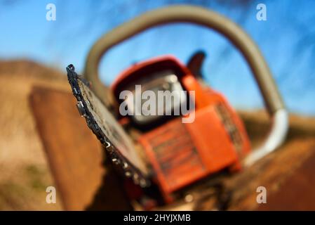 Detail der verschmutzten, gebrauchten Kettensägekette zum Schneiden von Holz. Selektiver Fokus auf Verkettung. Unscharfer natürlicher Hintergrund Stockfoto