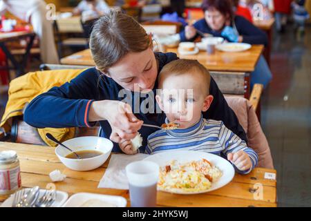 USCHHOROD, UKRAINE - 14. MÄRZ 2022 - Eine Frau füttert einen Jungen in einem Restaurant, das Binnenvertriebenen, die vor der russischen Invasion fliehen, kostenlose Mahlzeiten anbietet, Uschhorod, Region Zakarpattia, Westukraine. Foto von Hudak Serhii/Ukrinform/ABACAPRESS.COM Stockfoto