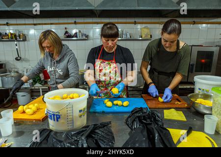 USCHHOROD, UKRAINE - 14. MÄRZ 2022 - drei Freiwillige schneiden Kartoffeln in einem Restaurant, das kostenlose Mahlzeiten für Binnenvertriebene anbietet, die vor der russischen Invasion fliehen, Uschhorod, Region Zakarpattia, Westukraine. Foto von Hudak Serhii/Ukrinform/ABACAPRESS.COM Stockfoto