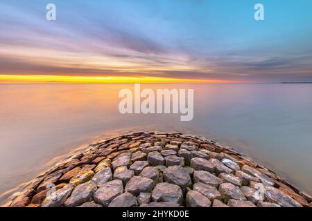 Typischer Bau von Basalt-Wellenbrechern am IJsselmeer in der Nähe der Stadt Hindeloopen in der Provinz Friesland bei Sonnenuntergang, Niederlande. Stockfoto