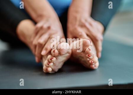 Zugeschnittenes Bild einer älteren Frau, die auf einer Sportmatte sitzt. Stockfoto