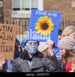 London, Großbritannien. 13.. März 2022. Ein Protestler hält ein Schild mit einer Sonnenblume und der Aufschrift "steht mit der Ukraine". Demonstranten versammelten sich vor der Downing Street zur Unterstützung der Ukraine, während Russland seinen Angriff fortsetzt. Stockfoto