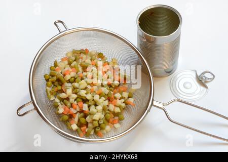 Russischer Salat in Küchensieb und Blechdose, Gemüsemischung Stockfoto