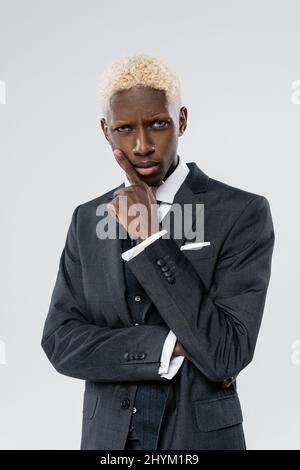 Blonde und ernsthafte afroamerikanische Mann mit blauen Augen isoliert auf grau Stockfoto