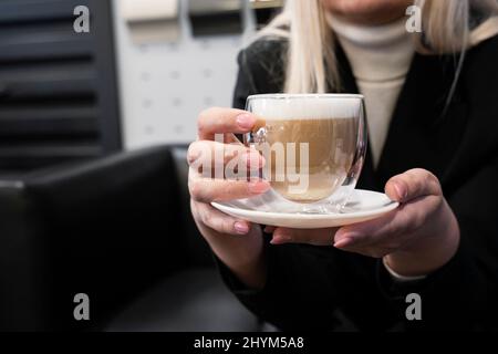 Mädchen in einem Autohaus hält Kaffee. Nahaufnahme des Kaffees. Stockfoto
