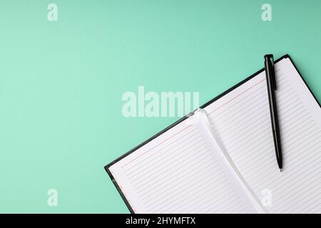 Leeres Notizbuch mit Stift auf mintgrün Hintergrund Stockfoto
