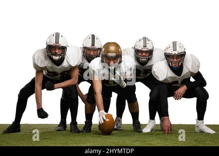 Startklar. Gruppe junger sportlicher Männer, professioneller amerikanischer Fußballspieler in Sportuniform und Ausrüstung, die isoliert auf Weiß posiert Stockfoto