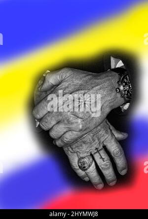 Zwei Hände mit Tätowierungen und im Hintergrund die Flaggen Russlands und der Ukraine Stockfoto