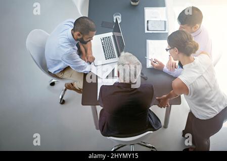 Einige Fakten und Zahlen durchgehen. Aufnahme von Geschäftsleuten, die in einem Büro ein Meeting abhalten. Stockfoto