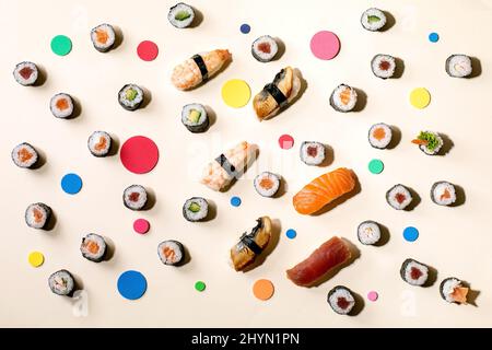 Sushi-Brötchen im Set. Traditionelles japanisches Sushi und Brötchen mit frischem Lachs, Thunfisch, Aal und Garnelen auf Reis, bunte Kreise auf beigem Hintergrund mit Stockfoto