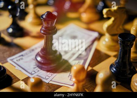 Geld in US-Dollar-Scheinen auf einem alten Schachbrett mit Retro-Schachfiguren Stockfoto