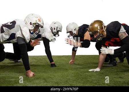 Startklar. Gruppe junger sportlicher Männer, professioneller amerikanischer Fußballspieler in Sportuniform und Ausrüstung, die isoliert auf Weiß posiert Stockfoto