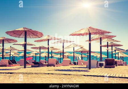Strohschirme und Liegestühle am Strand. Budva, Montenegro, Balkan, Europa. Beauty-Welt. Retro-Filter. Instagram Toning-Effekt. Stockfoto