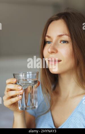 Porträt einer jungen Frau, die reines Glas Wasser trinkt, Nahaufnahme. Stockfoto