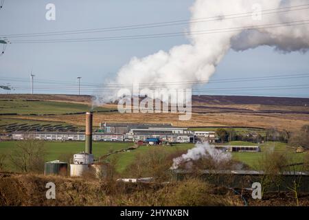 Dampfpumpen aus dem Kamin der Robinson- und Mitchells-Fabrik in der Nähe von Thornton, Bradford, England, West Yorkshire, Großbritannien. Dampf ist Wasser in der Gasphase. Dies kann durch Verdunstung oder durch Sieden auftreten, bei dem Wärme aufgebracht wird, bis das Wasser die Enthalpie der Verdampfung erreicht. Gesättigter oder überhitzter Dampf ist unsichtbar; „Team“ bezieht sich jedoch häufig auf nassen Dampf, den sichtbaren Nebel oder Aerosol von Wassertropfen, die sich aus der Kondenierung von Wasserdampf bilden. Kredit: Windmill Images/Alamy Live Nachrichten Stockfoto