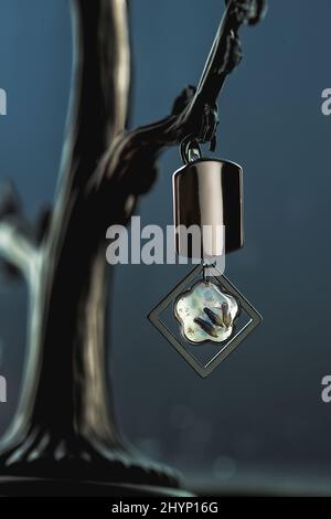 Vertikale Aufnahme eines schwarzen ornamentalen Ohrrings, der an einem künstlichen Baum hängt Stockfoto