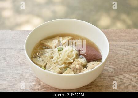 Vietnamesische Reisnudeln oder Pho mit Wurst in Scheiben schneiden und Schweinefleisch in einer Suppe auf einer Schüssel hacken Stockfoto
