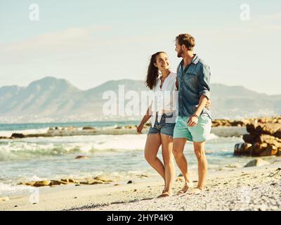 Wir teilen eine tiefe Liebe zum Strand. Aufnahme eines jungen Ehepaares, das am Strand läuft. Stockfoto