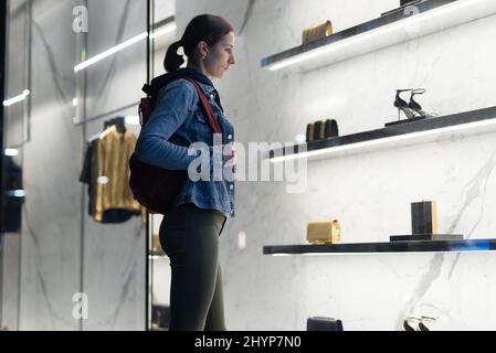 Frau steht an einem Schaufenster und schaut auf Schuhe Stockfoto