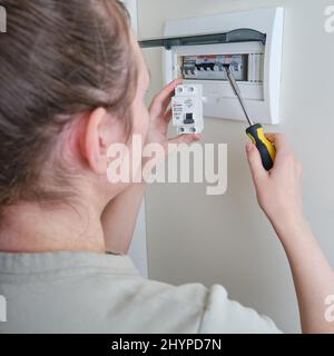 Eine Frau wechselt eine automatische Sicherung EKF in einer elektrischen Zentrale zu Hause. Selbstreparatur und Austausch von elektrischen Geräten in der Wohnung, diy - Moskau, Stockfoto