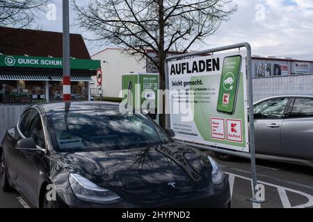 Tettnang, Deutschland - 18. Februar 2022: Eine statische Aufnahme eines soliden schwarzen Tesla Model 3 Dual-Motors, der auf der Kaufland Supermarkt DC-Ladestati geladen wird Stockfoto