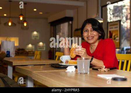 Glückliche Latina-Frau beim Frühstück in einem Café. Stockfoto