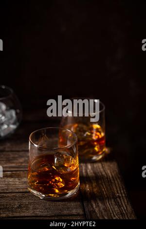 Zwei Gläser des Whiskys mit Eis isoliert auf einem Dunkler Hintergrund Stockfoto