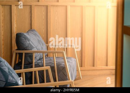 Seitenansicht des Komforts Einzelsessel Gesicht zu warmem Licht von außen, innere Holzwand, Platz für Kopie, keine Menschen Stockfoto