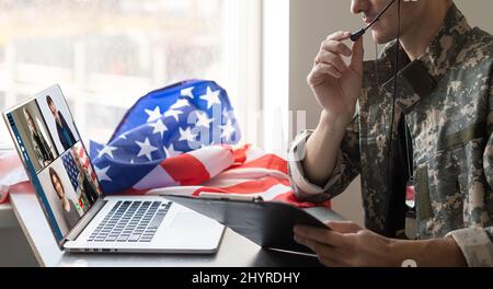 Reifer männlicher Soldat, der im Hauptquartier einen Laptop für die Kommunikation mit seiner Familie verwendet. Stockfoto