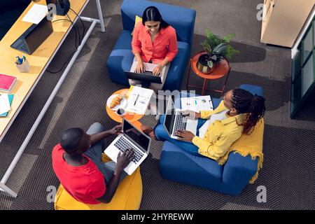 Ein Blick aus der Perspektive auf Geschäftsleute, die auf Laptops arbeiten, während sie in einem modernen Büro sitzen Stockfoto