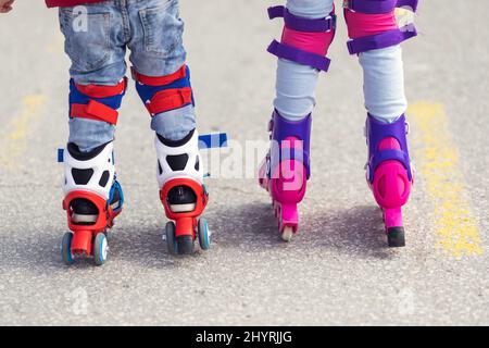 Kinder junge und Mädchen mit Spaß im Freien, während Roller Schlittschuhe reiten. Kinder auf Rollerblades. Rollschuhlaufen im Park in der Nähe der Küste. Stockfoto