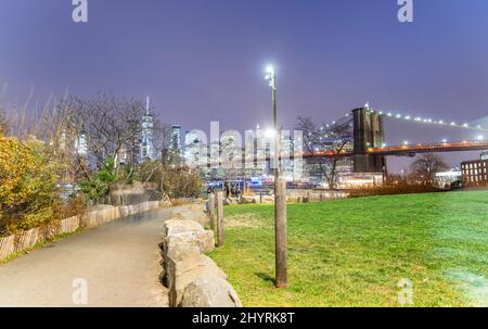 New York City. Die Brooklyn Bridge bei Nacht, Blick vom Main Street Park in Brooklyn. Stockfoto