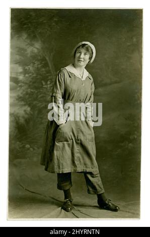 205-VBW1430 WW1 Postkarte aus der Ära der Munitionsarbeiterin, die stolz ihre Uniform zeigt, darunter Hosen, möglicherweise Yorkshire, Großbritannien, um 1917 Stockfoto