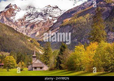 Sonnenuntergang Panorama von Kandersteg alte Kirche, Kanton Bern, Schweiz, Europa, Bäume im Herbst und den Sonnenuntergang Berge Panorama Stockfoto