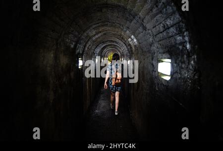 Weibliche Wanderung im Tunnel der Höhle von Natal Eingang in Terceira Insel, Azoren, Portugal Stockfoto