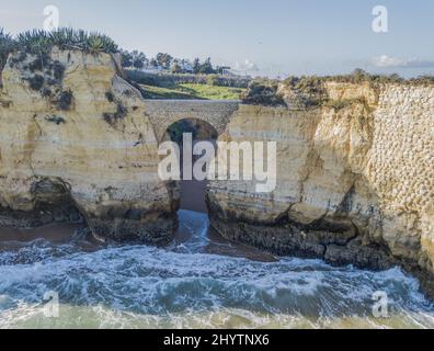 Alte römische Steinmetzbrücke am Strand Praia dos Estudantes in Lagos, Portugal Stockfoto