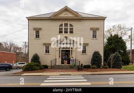 MCADENVILLE, NC, USA - 8. März 2022: McAden Memorial Hall, zwei Männer tragen Dekorationen. Stockfoto