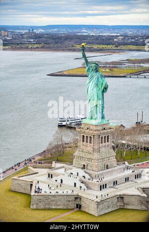 Freiheitsstatue auf Liberty Island und Fähre mit Touristen, New York City. Stockfoto