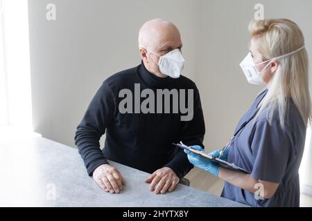 Arzt und älterer Mann mit Gesichtsmasken während des Coronavirus- und Grippeausbruchs. Schutz vor Viren und Krankheiten, Quarantäne zu Hause. COVID-2019. Stockfoto