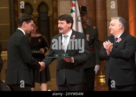 (220315) -- BUDAPEST, 15. März 2022 (Xinhua) -- der ungarische Präsident Janos Ader (C) verleiht dem Kurzstrecken-Eisschnellläufer Shaolin Sandor Liu (1. L) Das mittlere Kreuz des Verdienstordens von Ungarn in Anerkennung seiner sportlichen Bemühungen bei den Olympischen Winterspielen in Peking während einer Preisverleihung vor dem Nationalfeiertag in Budapest, Ungarn, am 14. März 2022. (Foto von Attila Volgyi/Xinhua) Stockfoto