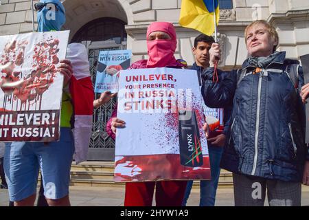 London, Großbritannien. 15.. März 2022. Ein Protestler trägt eine Balaclava und hält ein Plakat mit dem Deodorant Lynx und den Worten „Unilever, deine Präsenz in Russland stinkt“. Demonstranten versammelten sich vor dem Unilever-Hauptquartier am Victoria Embankment und forderten, dass das Unternehmen seine Geschäfte in Russland einstellt, während der Krieg in der Ukraine andauert. Kredit: Vuk Valcic/Alamy Live Nachrichten Stockfoto