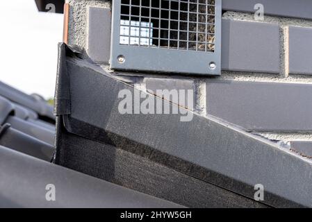 Systemkamin mit Blech bedeckt und mit Keramikfliesen bedeckt, sichtbares Gitter aus Schwerkraftlüftung. Stockfoto