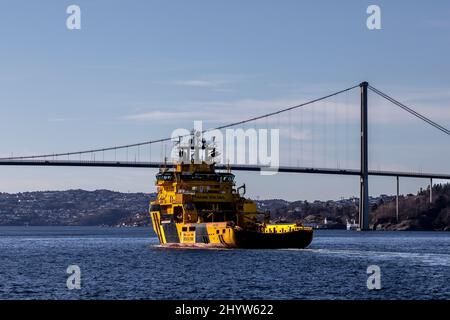 Offshore-Versorgung der Eisklasse AHTS Magne Viking in Byfjorden, vor dem Hafen von Bergen, Norwegen. Annäherung an die Askoybroen-Hängebrücke Stockfoto