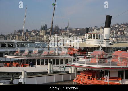 Decks von Dampfbooten in Luzern und Blick auf alte Häuser und eine Kirche im Hintergrund. Stockfoto